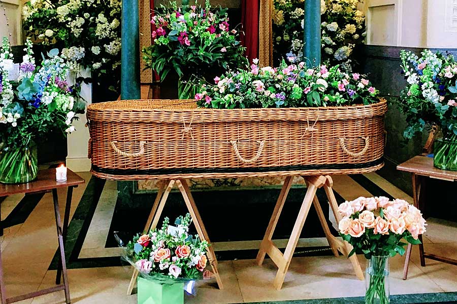 Funeral flowers with wicker coffin